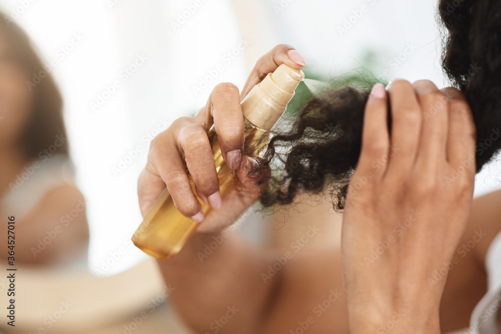 分叉补救措施。面目全非的黑人女性使用保湿喷雾卷发